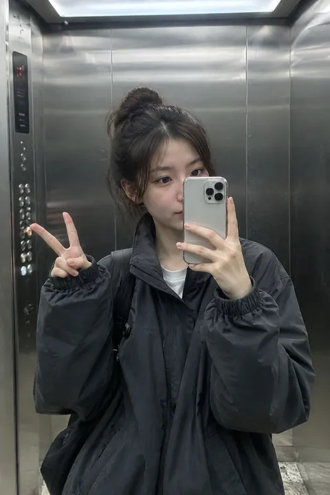 Young woman taking a mirror selfie in an elevator with a peace sign