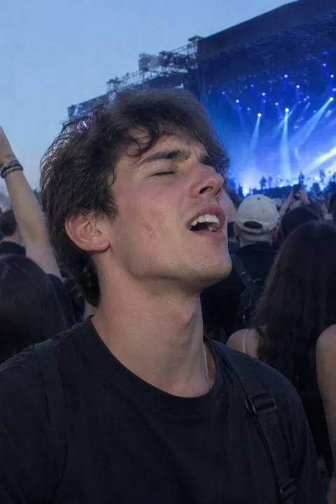 A young man singing along at an outdoor concert