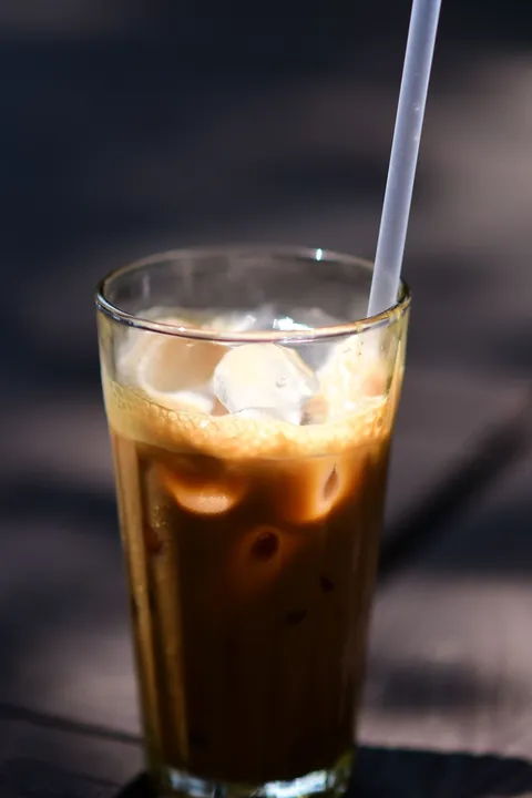 A glass of iced coffee with a straw on a table