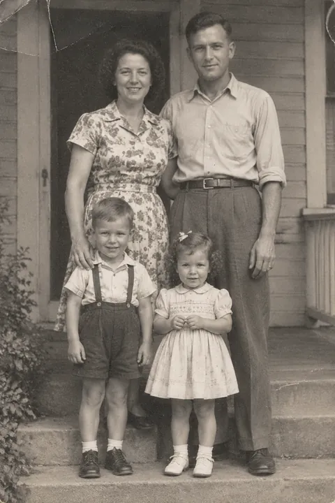 Vintage portrait of parents and two young children standing on porch steps